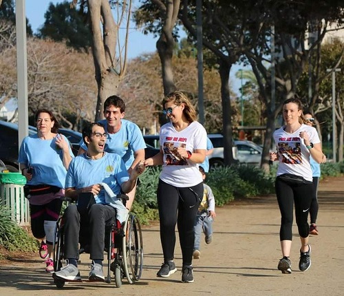 בחורות רצות ובחור רץ ומוביל בחור על כיסא גלגלים